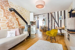 Una sala de estar moderna con pared de ladrillo, un sofá, un sillón amarillo y una chimenea.