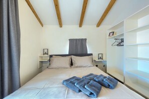 A bedroom with a bed, two bedside tables, a wardrobe, and a window with curtains. - Villa Pepa (Pazin)