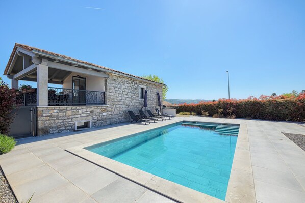 A stone building with a pool, outdoor seating, and a clear sky. - Villa Pepa (Pazin)