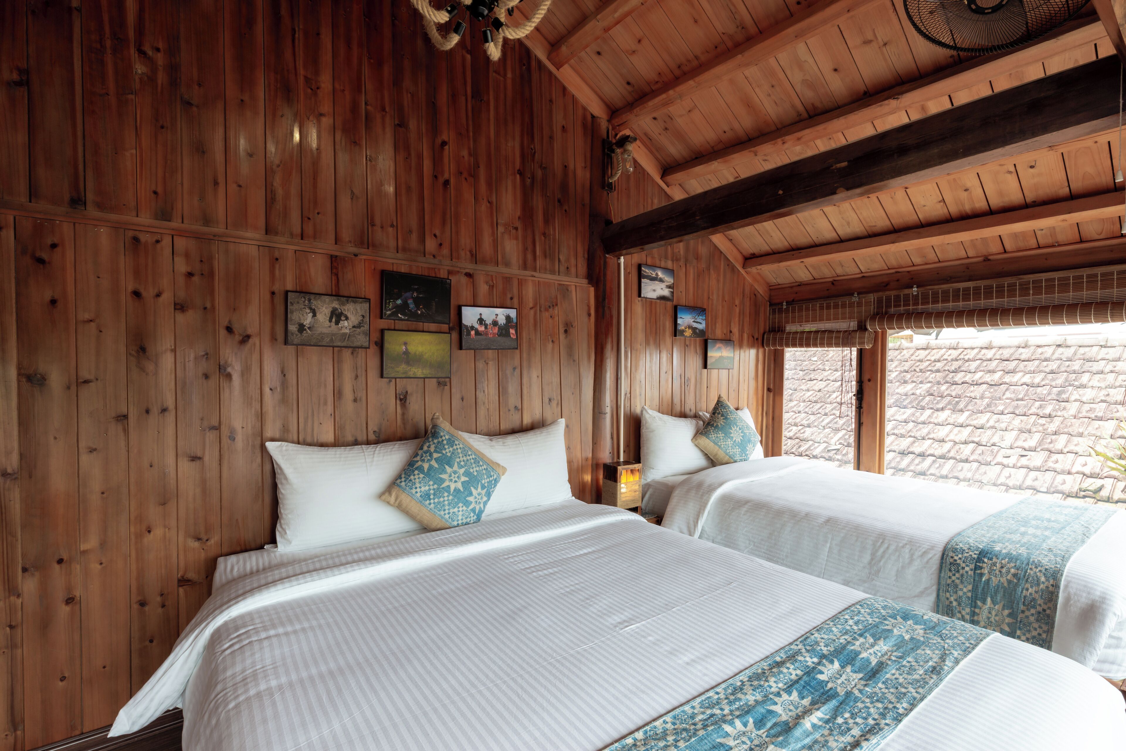 Una cabaña de madera con dos camas, cada una con una colcha blanca y un plaid azul estampada.
