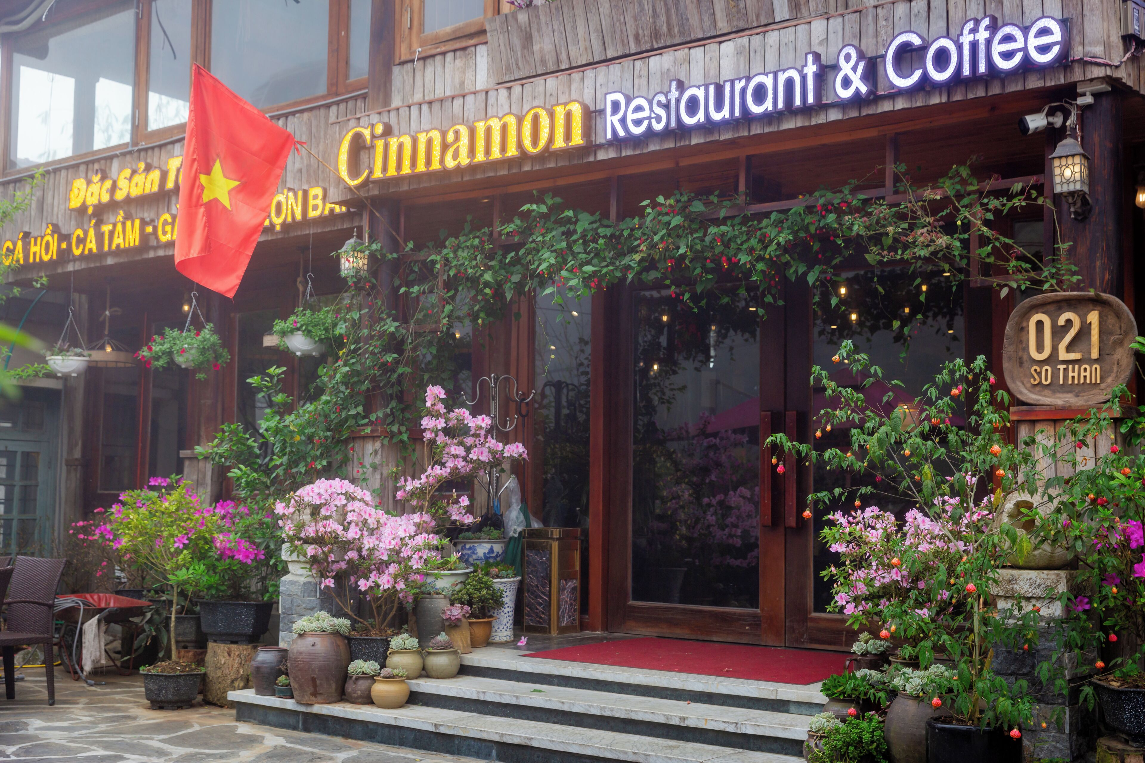 A restaurant with a wooden facade, outdoor seating, and potted plants.