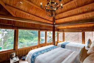 Un dormitorio de cabaña de madera con dos camas, ventanas amplias y una araña.