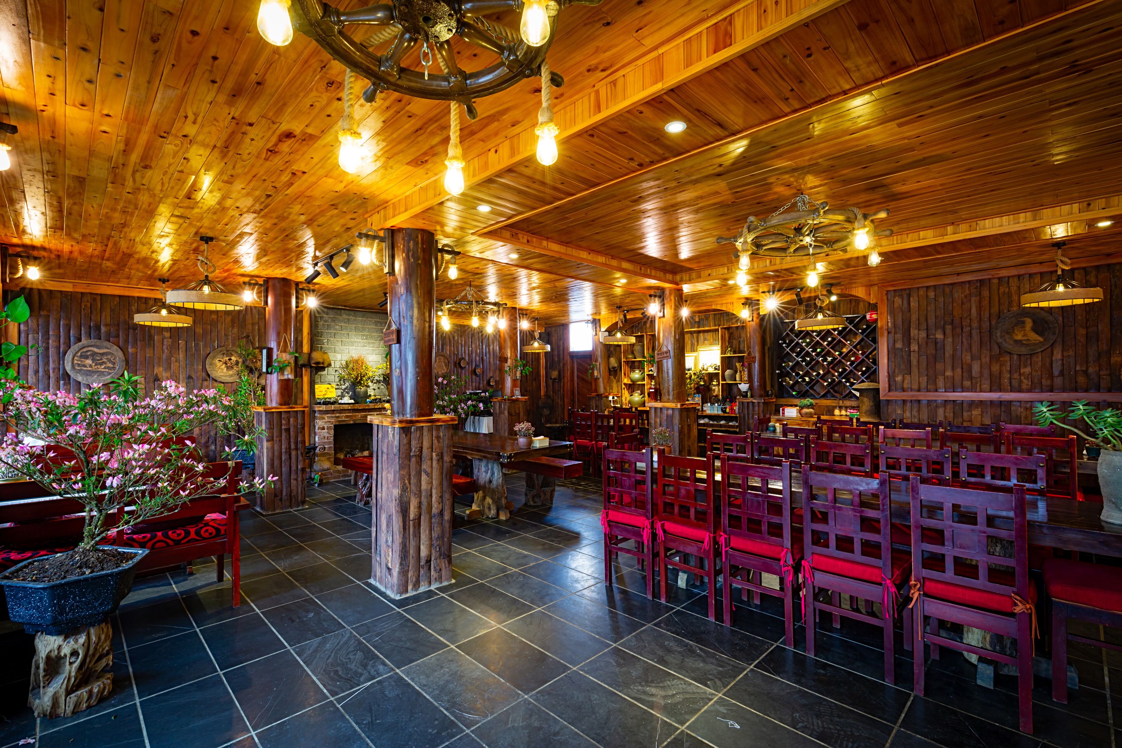 A restaurant with wooden interior, red chairs, and a central wooden table.
