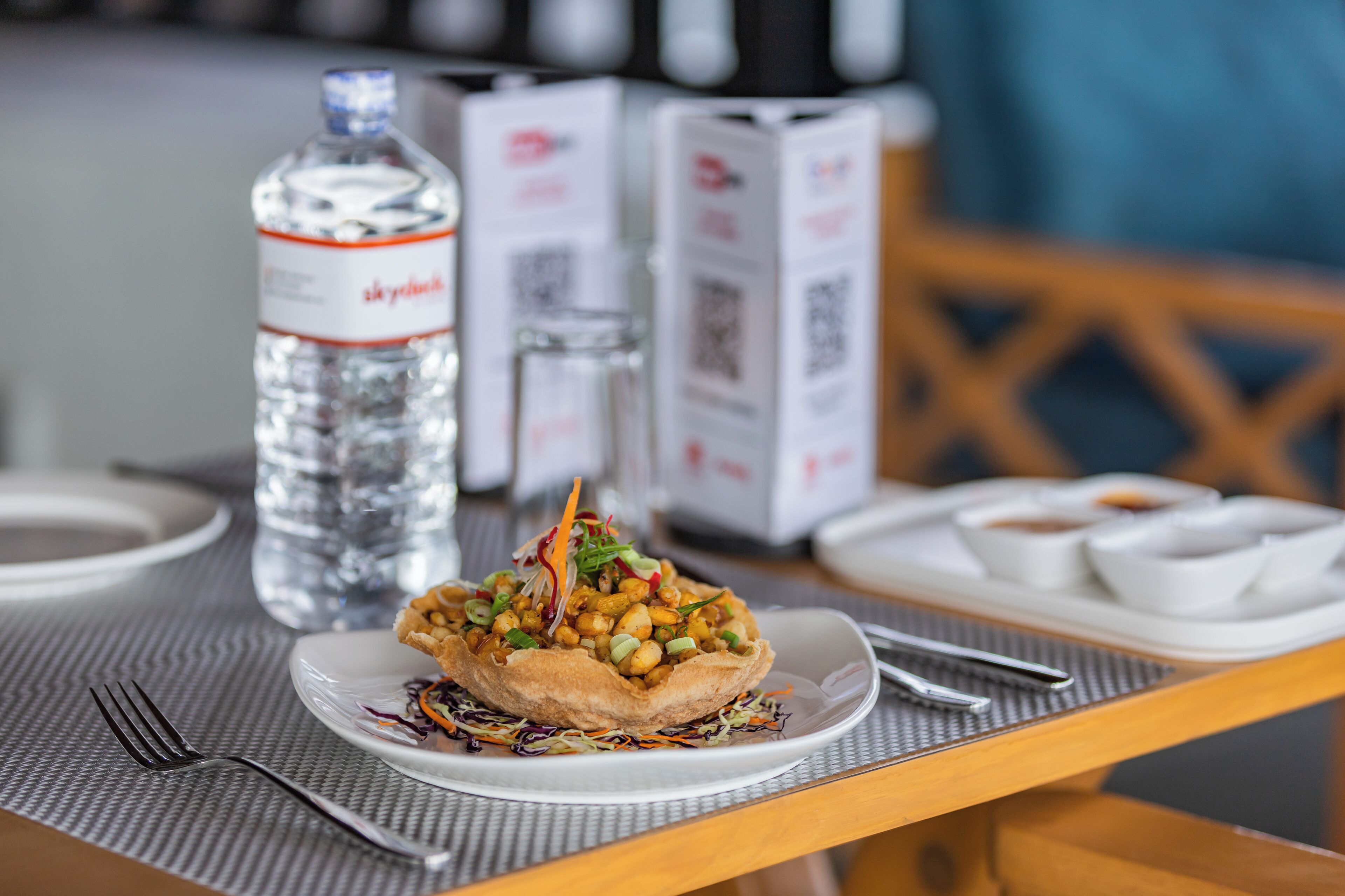 A table with a plate of food, a bottle of water, and a menu.