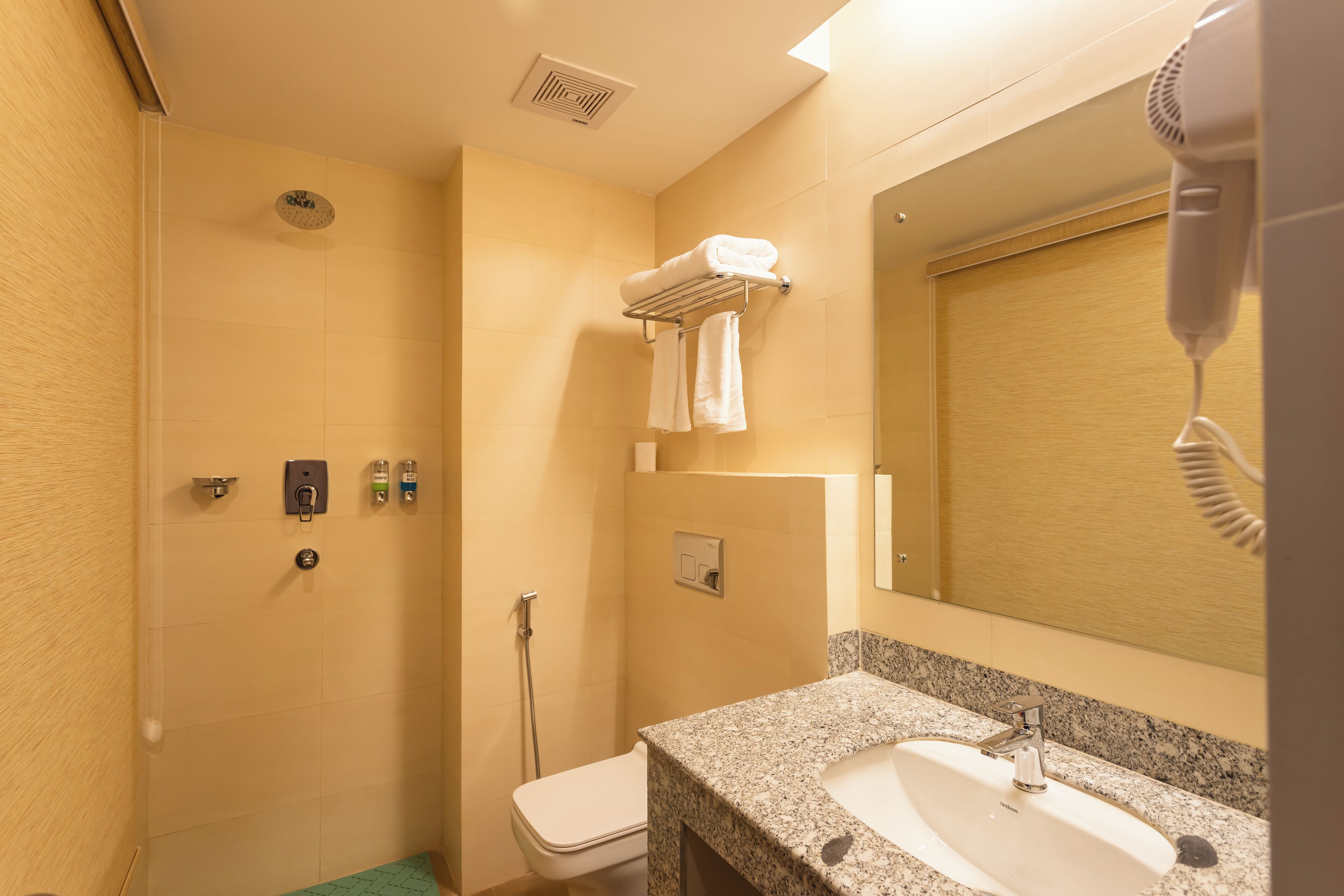 A bathroom with a shower, toilet, sink, and a hairdryer.