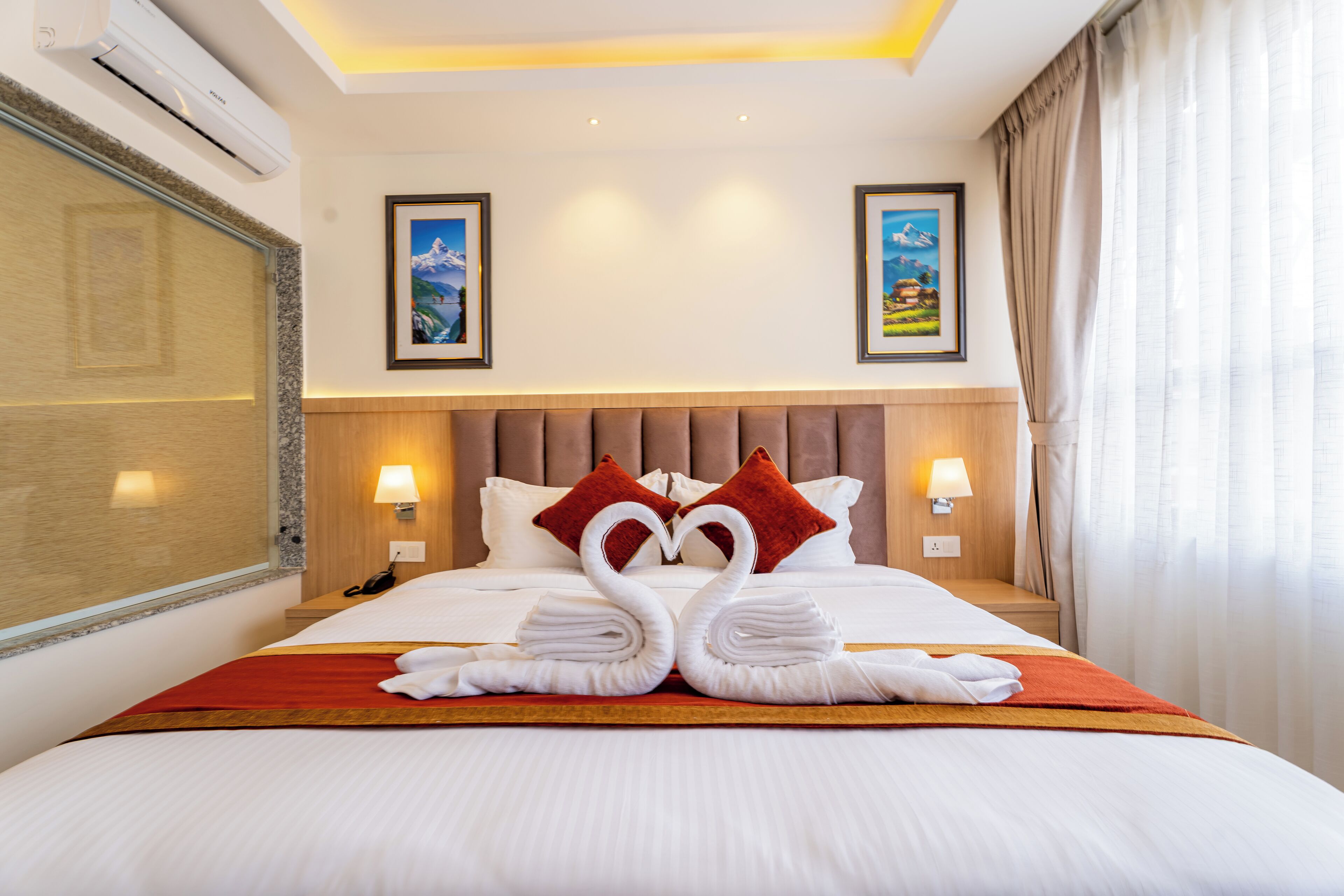 Una habitación de hotel con una cama bien hecha, dos cuadros en la pared y una ventana con cortinas.