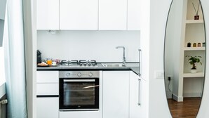 A modern kitchen with white cabinets, a gas stove, an oven, and a sink. - Domina Apartments Roma - San Pietro 1 (Roma)