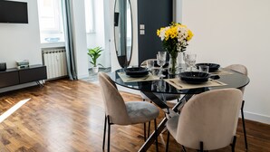 A modern dining area with a glass table, black plates, and a vase of yellow flowers. - Domina Apartments Roma - San Pietro 1 (Roma)