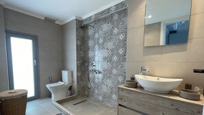 Ein modernes Badezimmer mit barrierefreier Dusche, Toilette und Waschtisch mit großem Becken.
