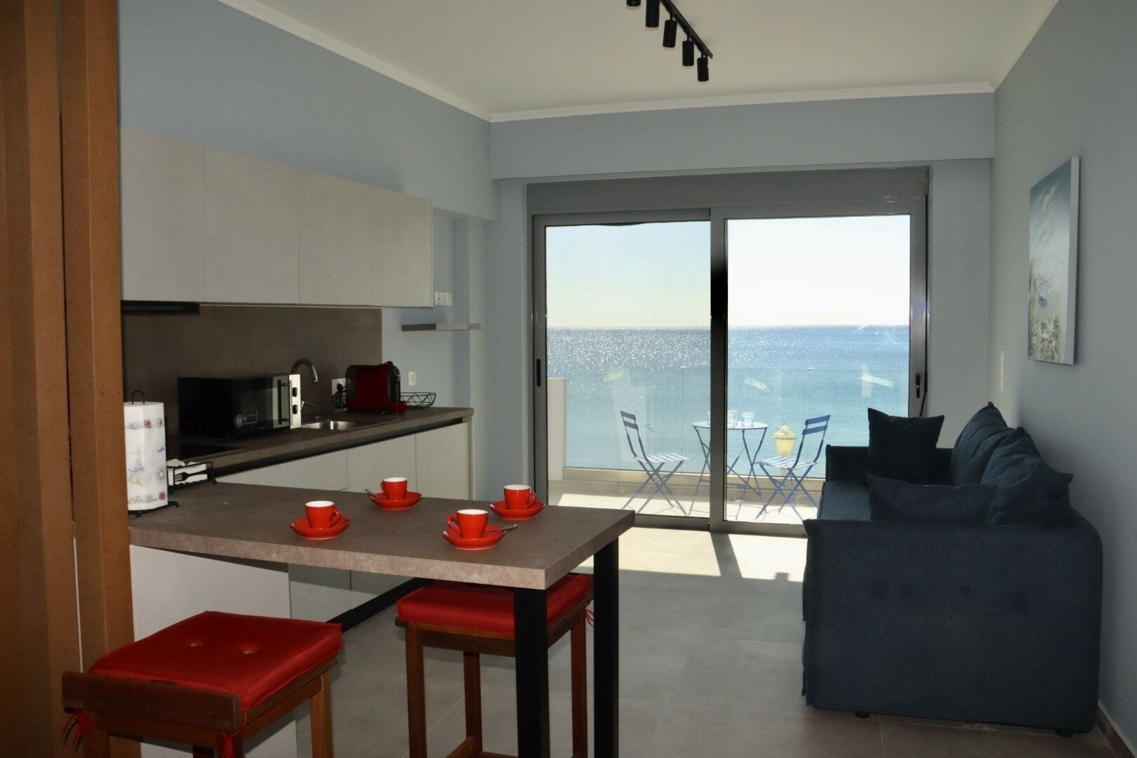 A compact living space with a kitchen, dining area, and a balcony with a view of the sea.