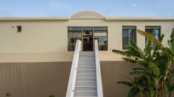 A building with a covered staircase leading to a door with large windows. - Lodge Apartments  (Zakynthos)