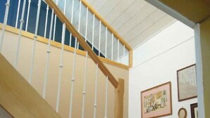 Una scala in legno con balaustre bianche che porta a un pianerottolo.