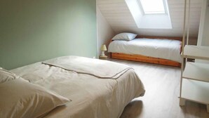 Una piccola e accogliente camera da letto mansardata, con tetto spiovente, finestra sul tetto e un letto a castello.