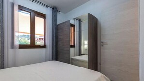 Um quarto com cama, janela, espelho e porta.