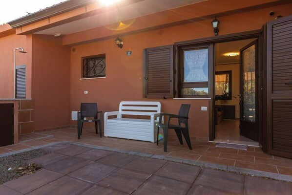 Edificio con un patio que incluye un banco blanco, dos sillas y una pequeña mesa.