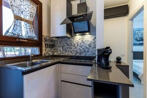 A modern kitchen with a sink, stove, and microwave. - A wonderful two-bedroom apartment situated just a short walk away from the sea in Costa Rei. (Costa Rei)