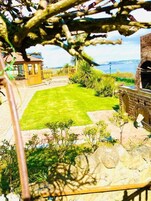 A well-maintained garden with a lawn, a brick structure, and a view of the sea.