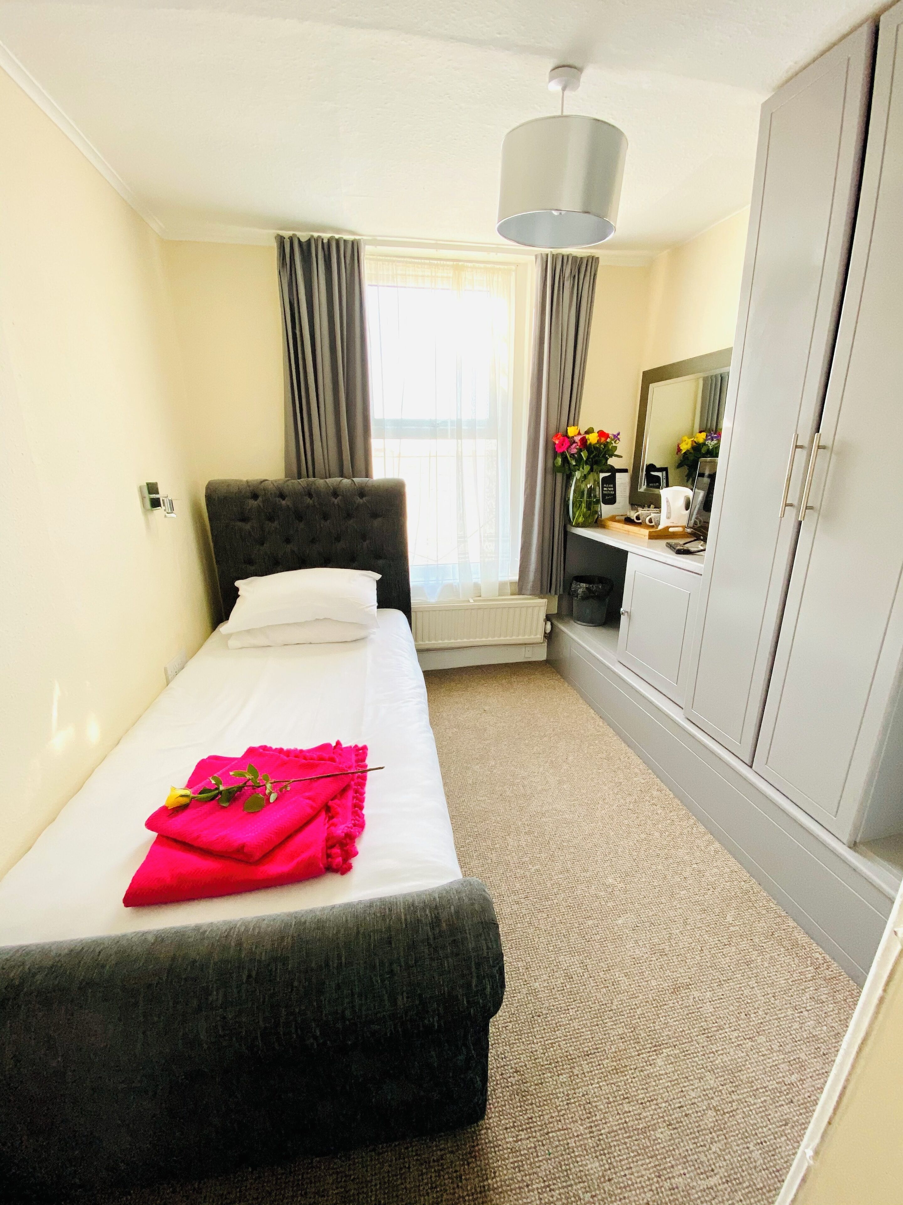 Een hotelkamer met een bed, een kledingkast, een radiator en een raam met gordijnen.