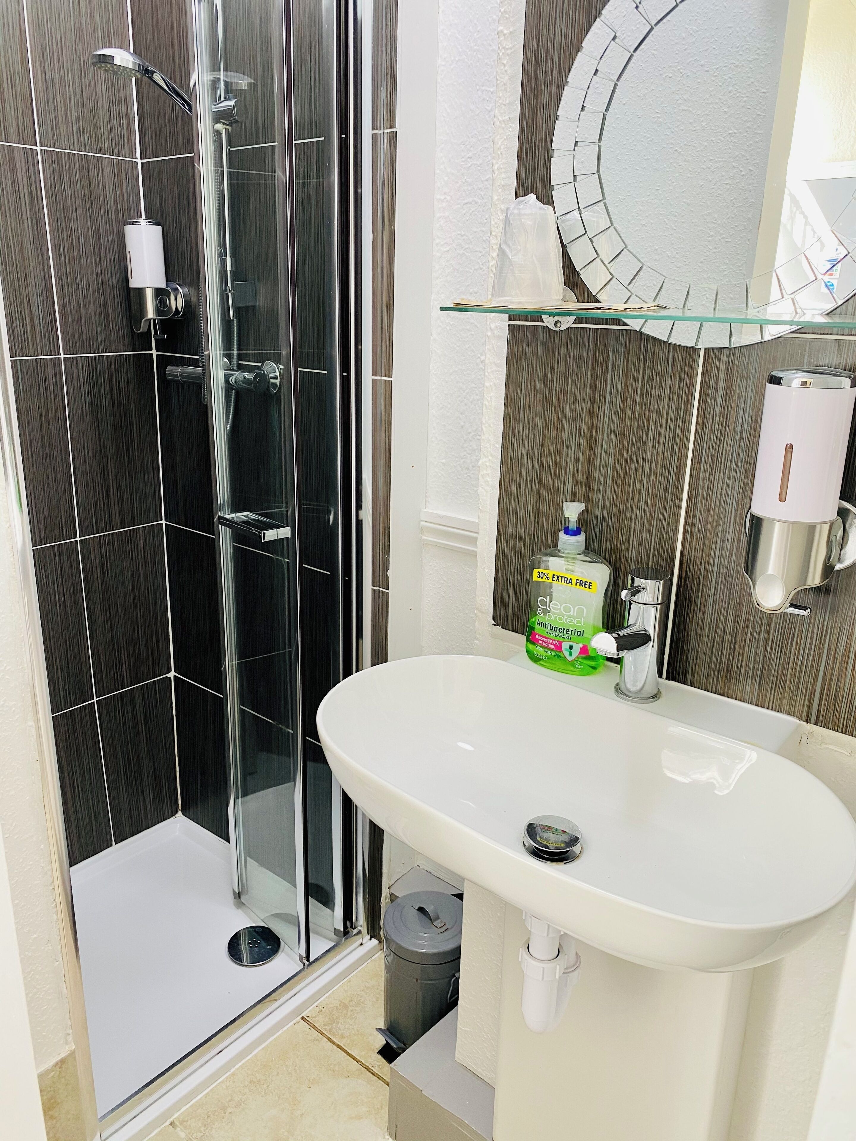 A bathroom with a glass-enclosed shower, a white sink, and a mirror above the sink.