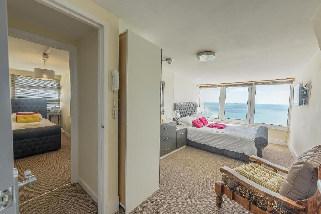 A bedroom with a bed, bedside table, and a view of the sea.