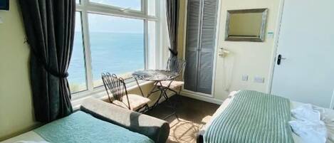 Una habitación de hotel con dos camas, un escritorio y vista al mar.
