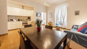 A modern kitchen with white cabinets, a dining table, and a potted plant. - Casa Zamia by Mmega (Florence)