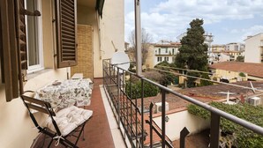 A balcony with a table and chairs, a view of the surrounding buildings, and a railing. - Casa Zamia by Mmega (Florence)