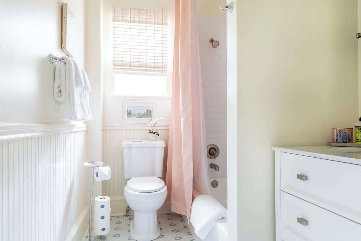 Et badeværelse med toilet, brusebad og et vaskeskab med skuffer.