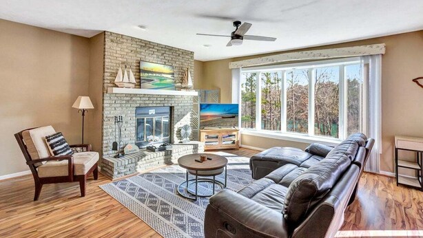 A living room with a fireplace, a sofa, a chair, and a large window.