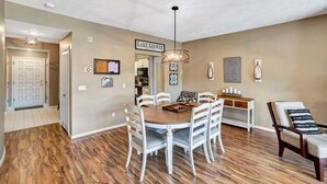 A dining area with a round table, white chairs, a hanging light fixture, and a sign reading "LAKE KOWEE".