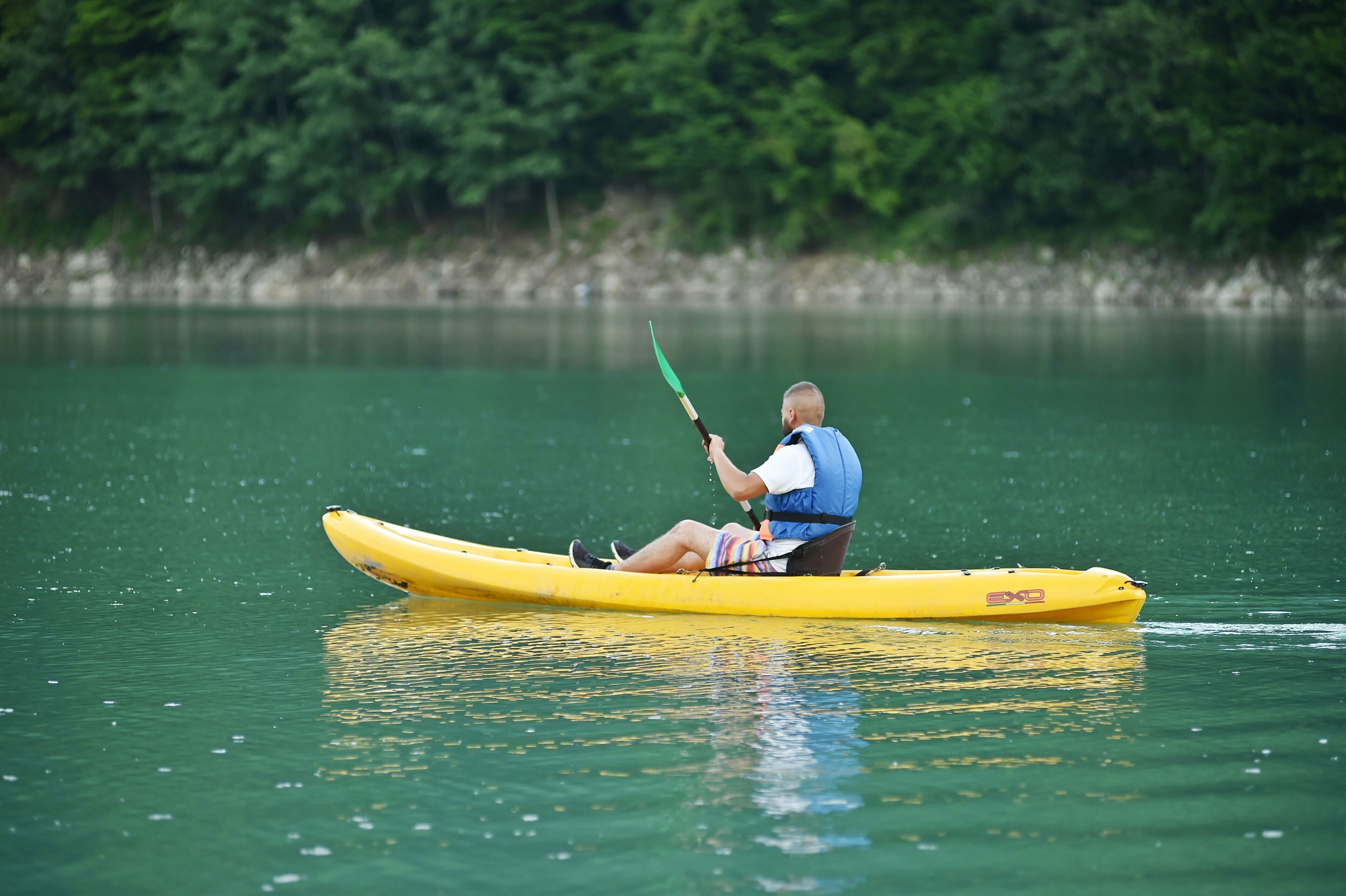 A person in a yellow kayak on calm water.