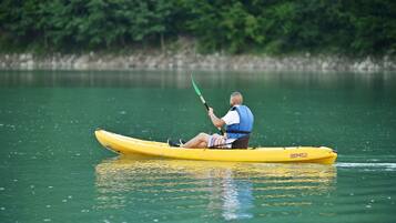 A person in a yellow kayak on calm water.