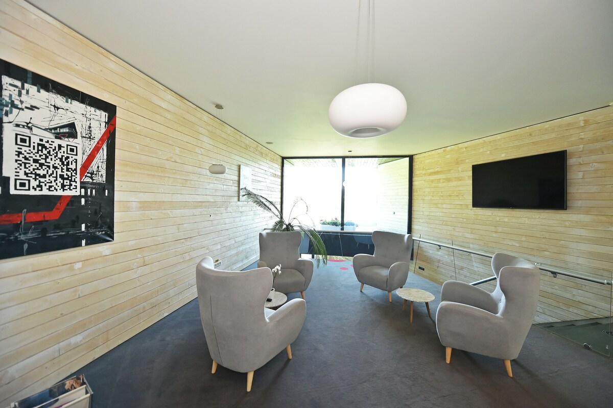 A modern interior with wooden panel walls, a large window, and a flat-screen TV mounted on the wall.