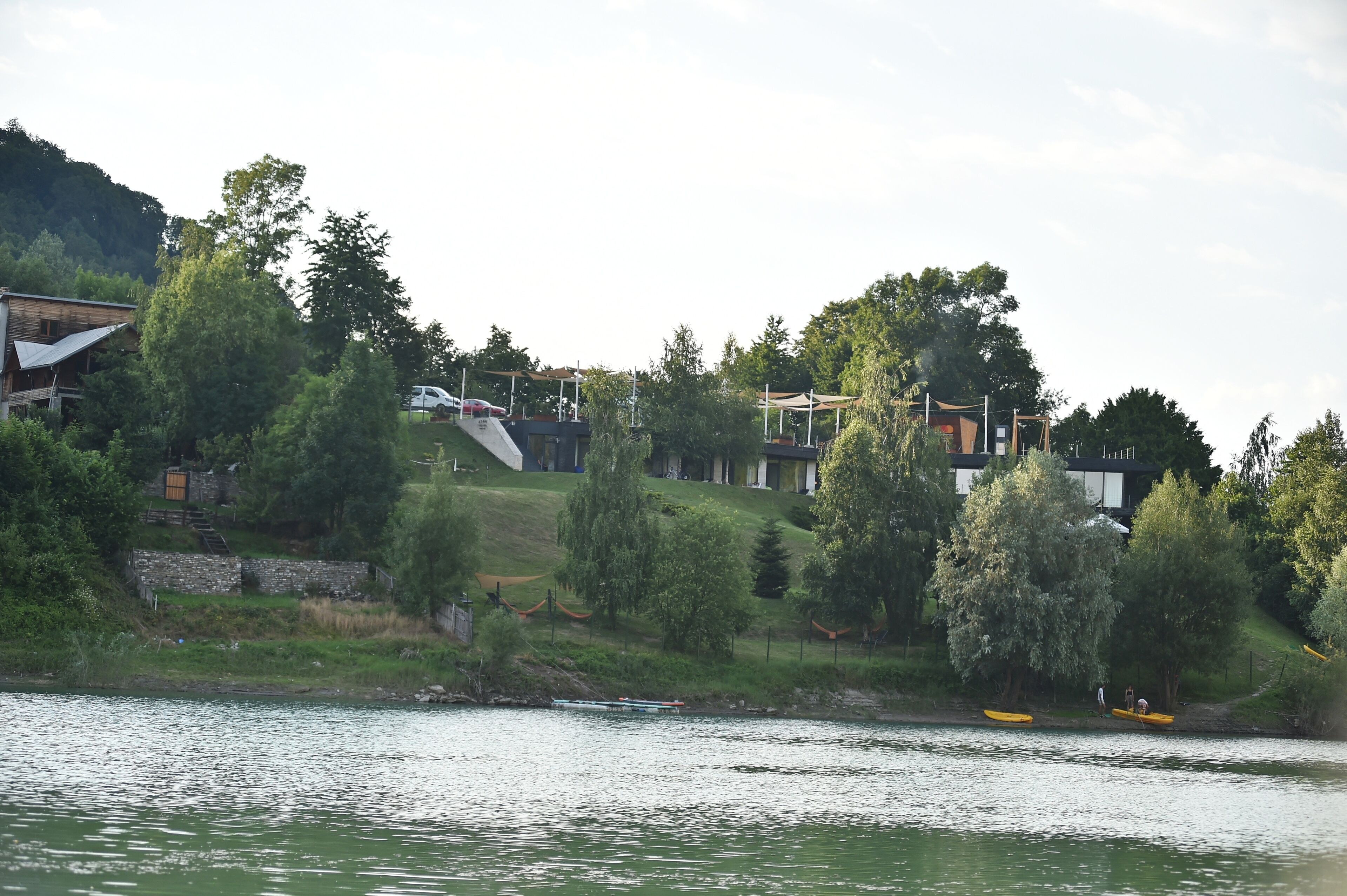 A riverside property with a building, trees, and a kayak on the water.