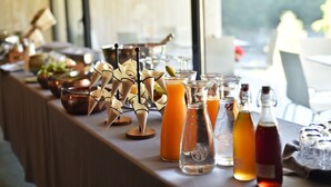 Una mesa de buffet con diversos alimentos, bebidas y centros de mesa decorativos.