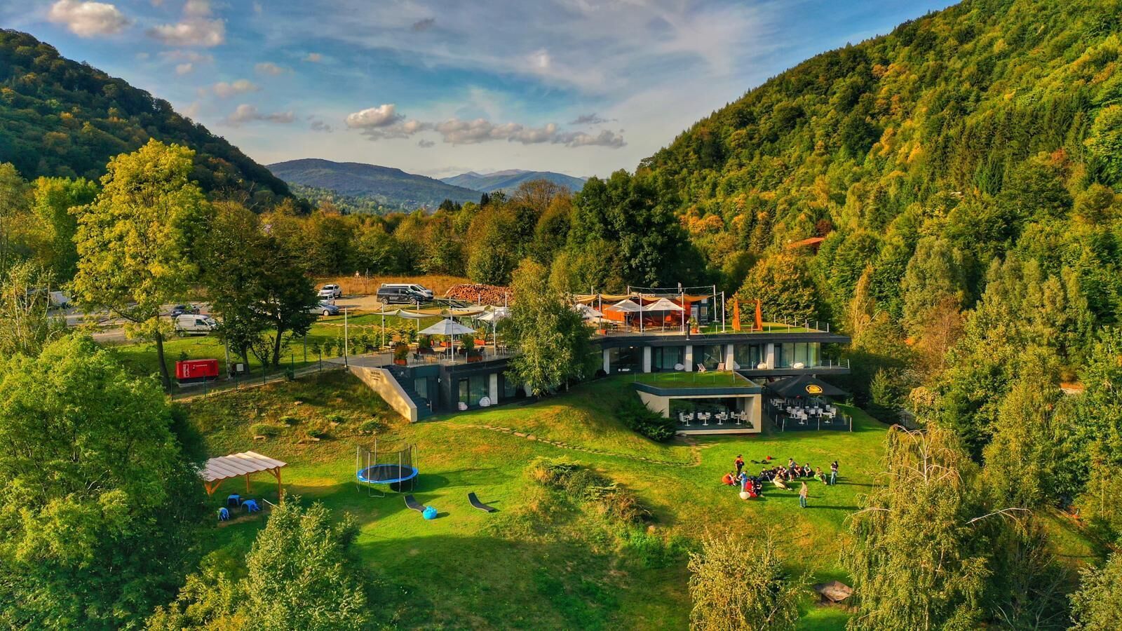 A resort with a pool, outdoor seating, and a view of the surrounding forest.