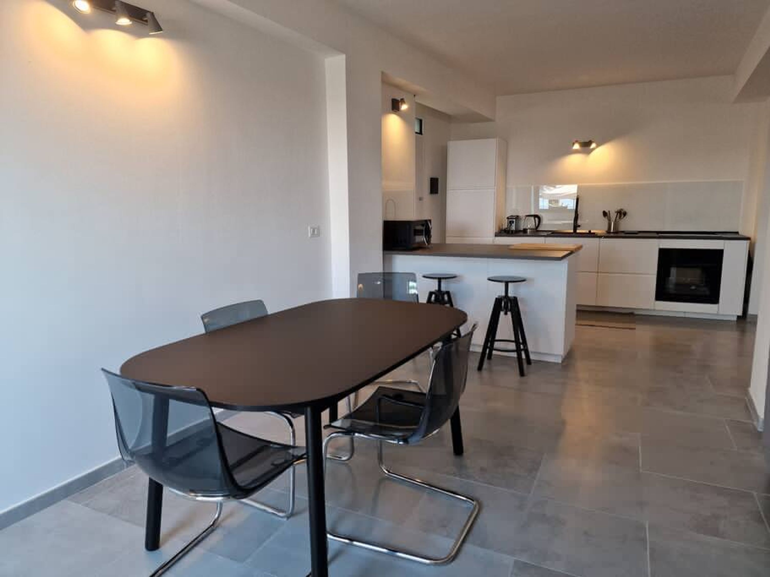 Una cocina moderna con una isla central, taburetes de bar y una mesa de comedor con sillas.