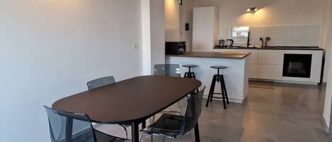 Una cocina moderna con una isla central, taburetes de bar y una mesa de comedor con sillas.