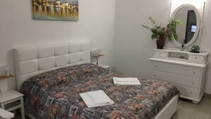 A bedroom with a bed, a nightstand, a dresser, a mirror, and a painting on the wall. - Villa Bonaccorso - Il Casotto il Limone Verde (Viagrande)