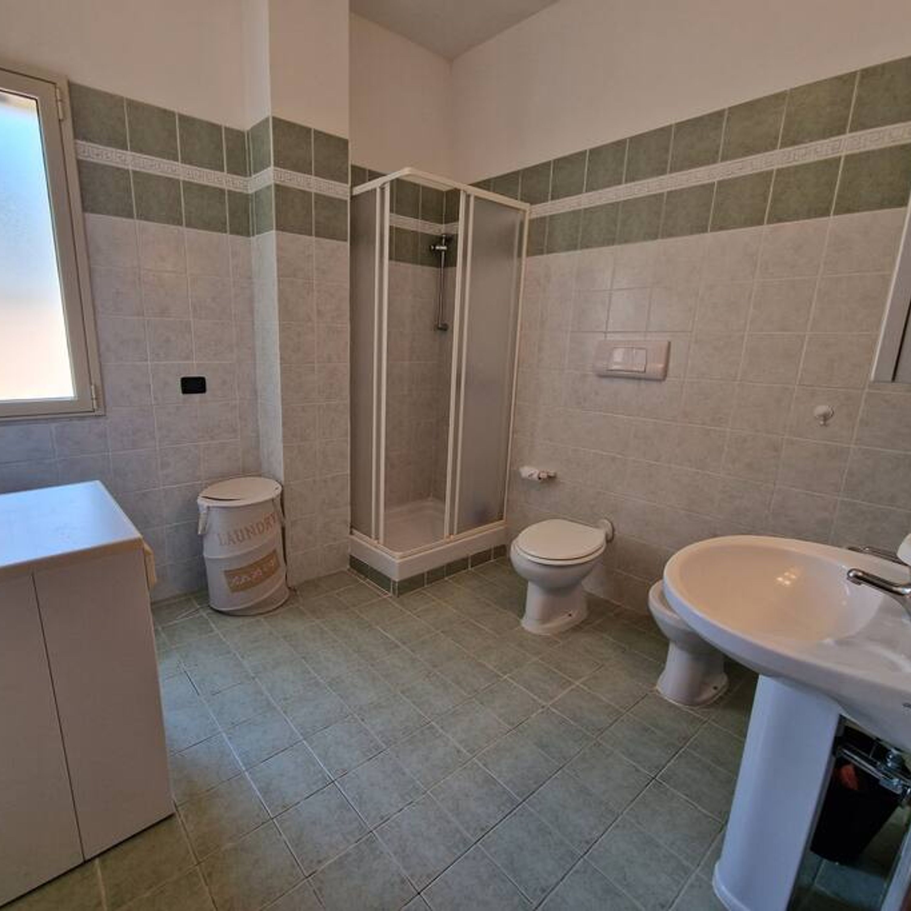 Une salle de bain avec douche, toilettes et lavabo.