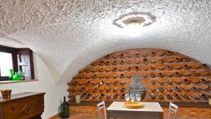 A dining area with a stone wall, a wooden table, and chairs. - Villa La Timpa con Jacuzzi Privata e Meravigliosa Vista Dell Etna e del Mare (Acireale)