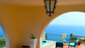 A terrace with a table and chairs, a potted plant, and a view of the sea. - Villa La Timpa con Jacuzzi Privata e Meravigliosa Vista Dell Etna e del Mare (Acireale)