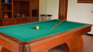 A pool table with a green felt surface, wooden frame, and two cue sticks.