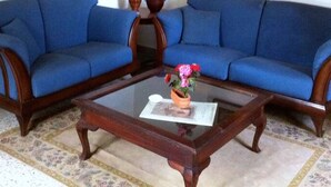 A living room with a blue sofa set, a wooden coffee table, and two paintings on the wall.