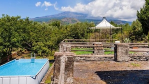 A swimming pool, a gazebo, and a mountainous landscape in the background.