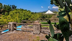 A rustic outdoor area with a wooden fence, a stone structure, and a white tent.