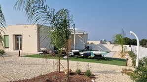 A modern building with a pool, outdoor seating, and a well-maintained garden. - Villa Elisia - Villetta con Piscina Privata (Augusta)
