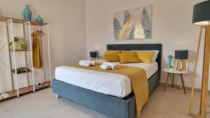 A bedroom with a bed, a wardrobe, a nightstand, and a painting on the wall. - Villa Elisia - Villetta con Piscina Privata (Augusta)