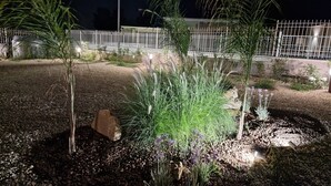 A landscaped garden area with gravel paths, various plants, and a white fence in the background. - Villa Elisia - Villetta con Piscina Privata (Augusta)