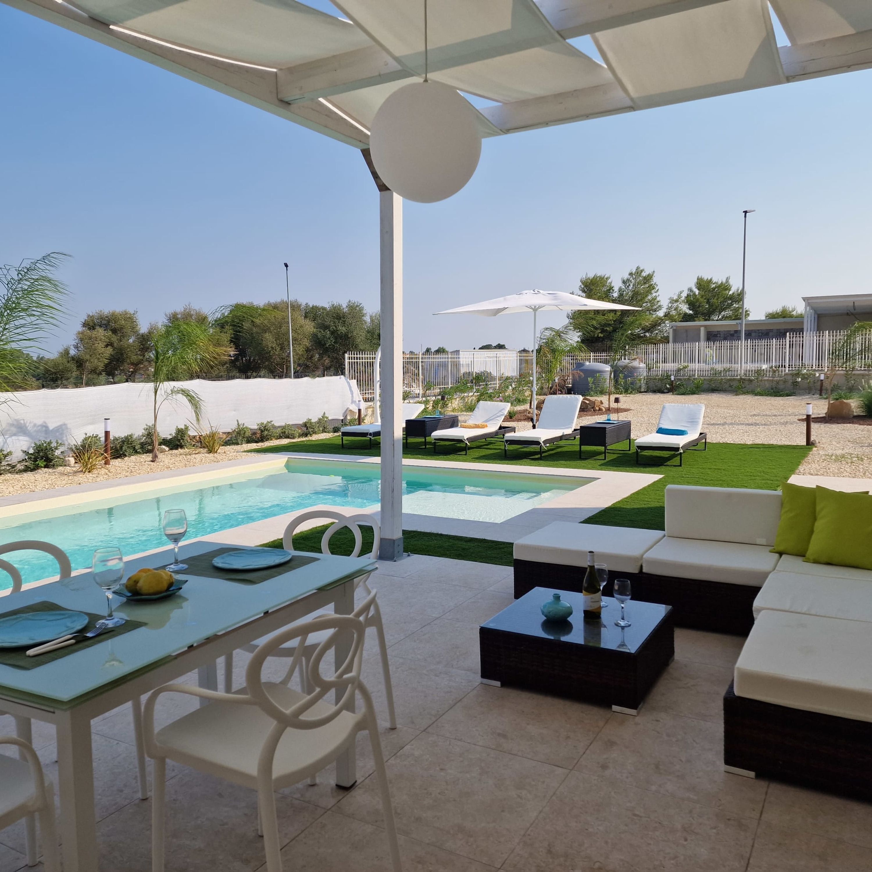 A poolside area with a table set for dining, lounge chairs, and a covered seating area.